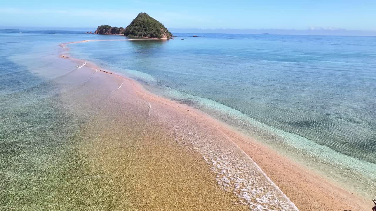 Lone man walking on a long sand strip between tropical islands in Philippines, aerial.