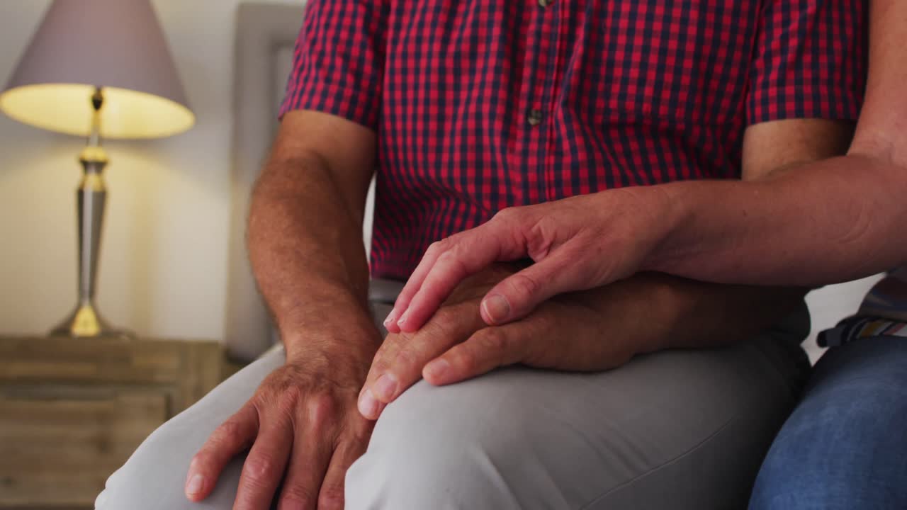 Coppia anziana caucasica a mezzo busto che si tiene per mano a casa