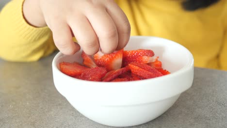 child eating sliced strawberries