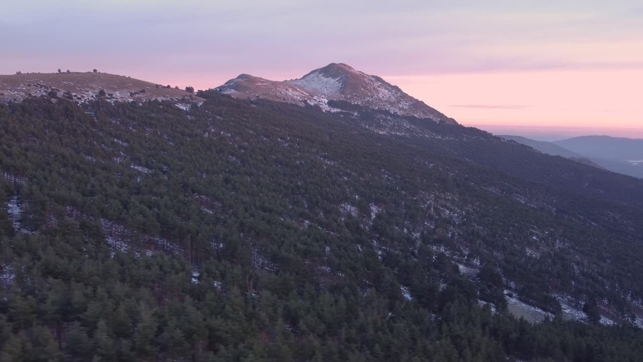 vista aérea de paralaje lateral durante la puesta de sol en invierno con nieve en los picos de las montañas en madrid, españa