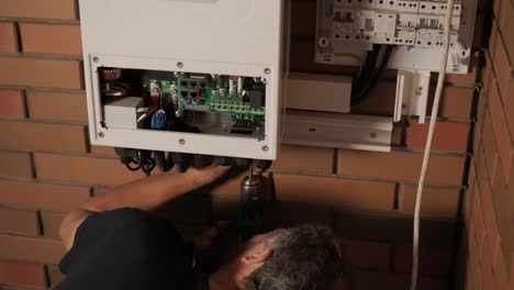 an electrician installing an inverter in a home. the image shows technical skill, modern tools, and attention to safety in electrical work