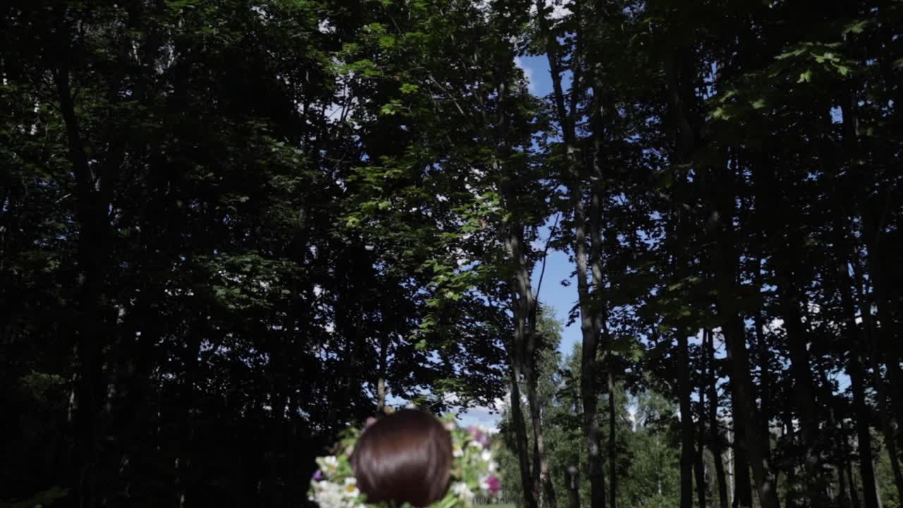 여름 동지, 자연 색상, 카메라가 나무 꼭대기와 하늘까지 기울어지고 슬로우 모션을 준비할 준비가 된 꽃관을 가진 여성