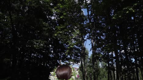 a woman with the flower crown ready to prepare summer solstice, natural colours, camera moves in and tilts up to the tree tops and the sky, slow motion