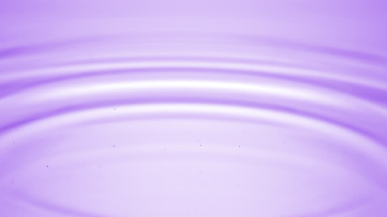 la gota de agua cae sobre la superficie del fluido púrpura creando anillos de agua
