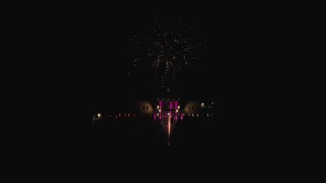 Filmische-Drohnenaufnahme-Aus-Der-Luft-Um-Ein-Wunderschönes-Feuerwerk-In-Der-Nacht-Mit-Einem-Alten-Großen-Italienischen-Villa-Lodge-Landhaus-Im-Hintergrund