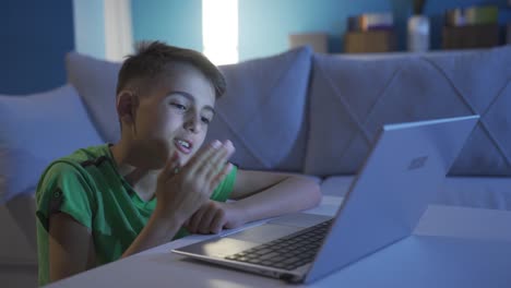 un niño haciendo una videollamada en una computadora portátil soplando el corazón a la cámara.
