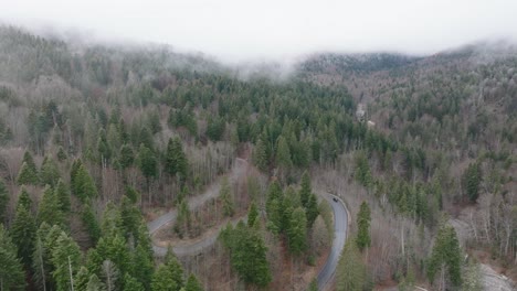 Toma-Aérea-En-El-Clima-Brumoso-De-La-Carretera-En-Zigzag-En-El-Corazón-De-Las-Montañas-Bucegi,-Rumania