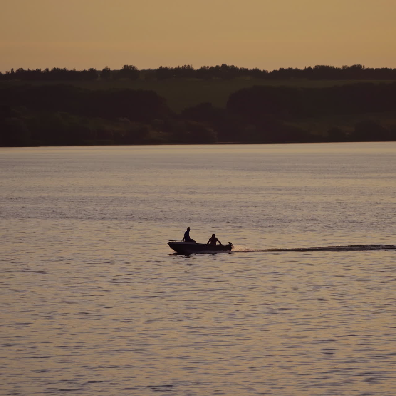 Motor boat floating in water on the forest background at dusk. Two people in a boat swimming along the river in the evening.