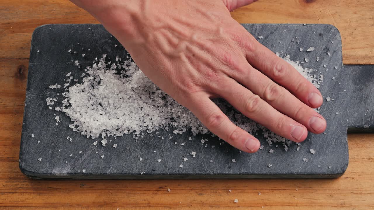 Hand sprinkling salt on a cutting board