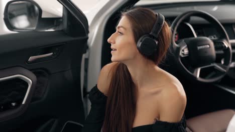 beautiful sexy girl sitting in the car listens to music on headphones