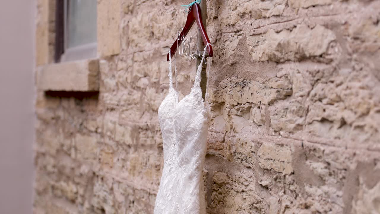 свадебное платье висит на деревянном вешалке перед каменной стеной внутри красивой церкви