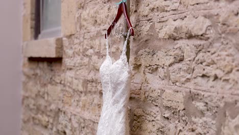 Vestido-De-Novia-Colgado-En-Una-Percha-De-Madera-Frente-A-Una-Pared-De-Piedra-Dentro-De-Una-Hermosa-Iglesia