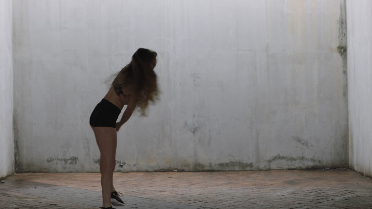 mujer bailarina hermosa joven bailarina de calle caucásica realizando movimientos contemporáneos disfrutando de la expresión de la danza moderna practicando en un almacén grungy