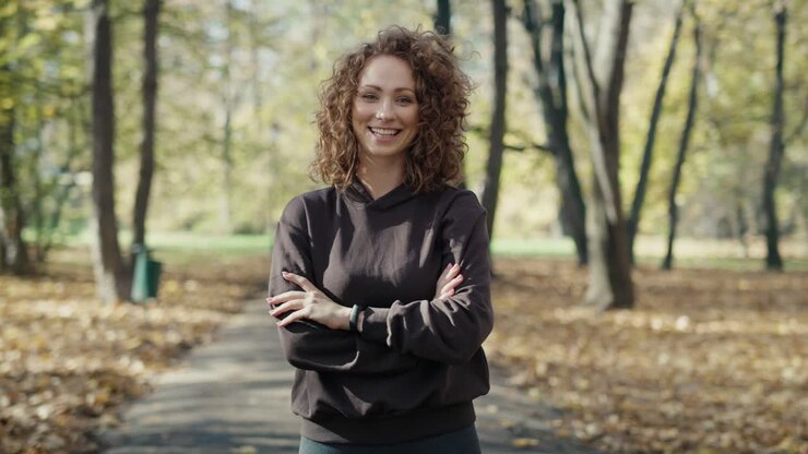 Ritratto di donna dai capelli rossi sorridente mentre fa jogging al parco