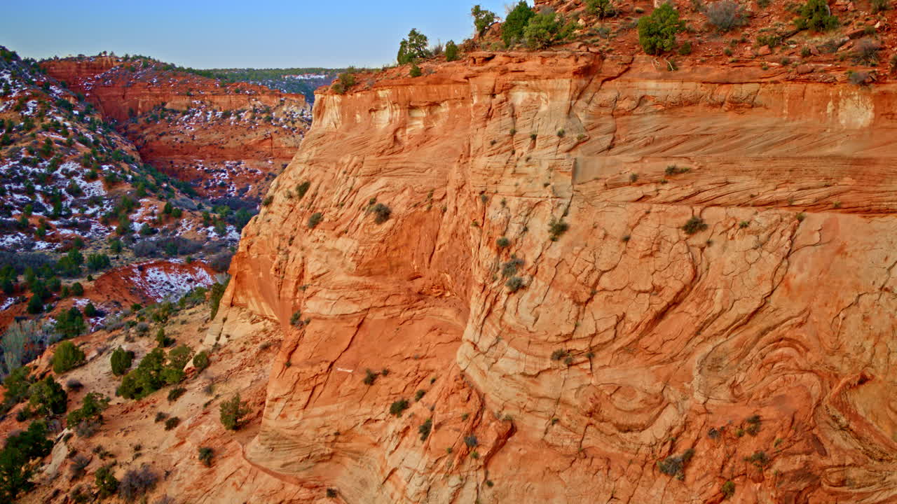 Overhead drone pass revealing fascinating textures within the red rock canyon face.