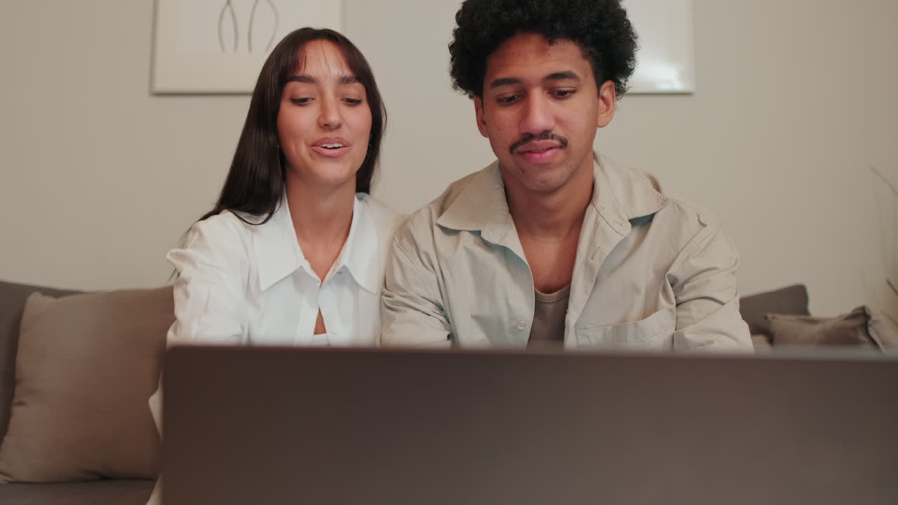 Joven pareja feliz viendo contenido en un portátil en casa