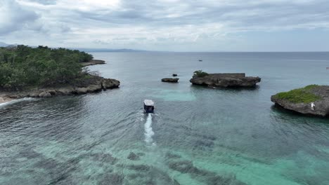 Aerial-view-following-a-boat-moving-in-middle-of-rocks,-in-Rio-San-Juan,-Dominican-republic