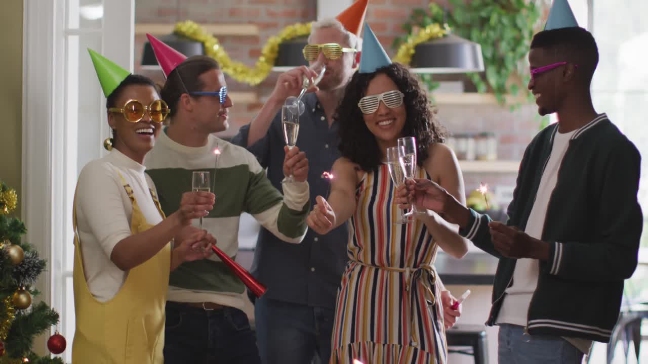 Happy group of diverse friends in party hats celebrating together, toasting with vine
