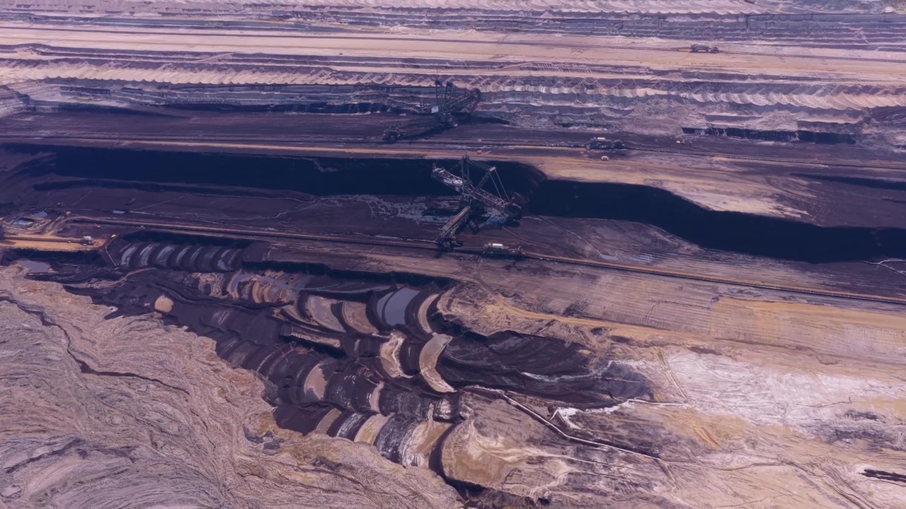 Aerial view of a massive bucket wheel excavator digging in a vast open cast lignite mine, showcasing industrial fossil fuel extraction
