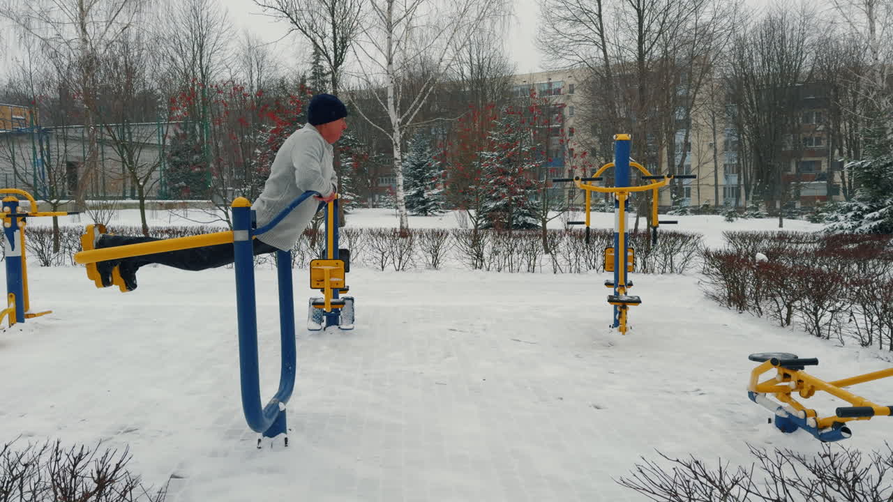 Senior man practicing healthy lifestyle. Caucasian male trains on the simulator outdoors in winter.