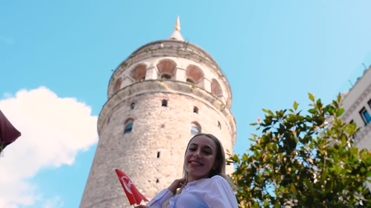 Joven atractiva y hermosa ondea la bandera turca frente a la Torre de Gálata, un lugar emblemático popular en Estambul, Turquía