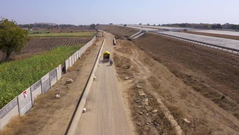 Pipes-Installed-Near-The-Public-Highway-With-A-Truck-And-Motorcycle-Driving-Through