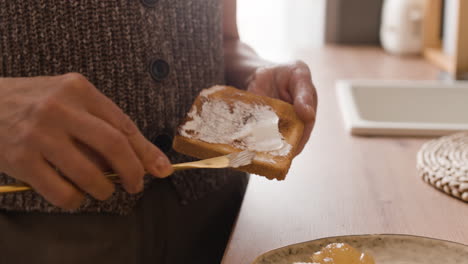 person spreading butter on toast in a kitchen