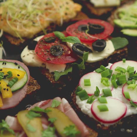 Variety-of-healthy-fresh-sandwiches-with-different-vegetables--herbs-and-ingredients-on-dark-table