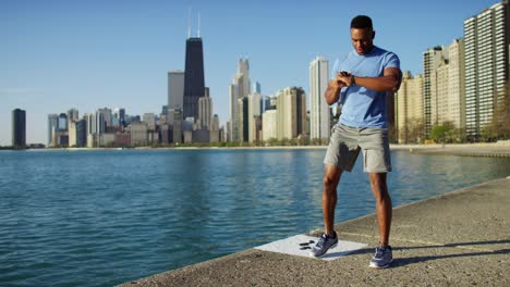 african american male stretching outdoors with smart watch