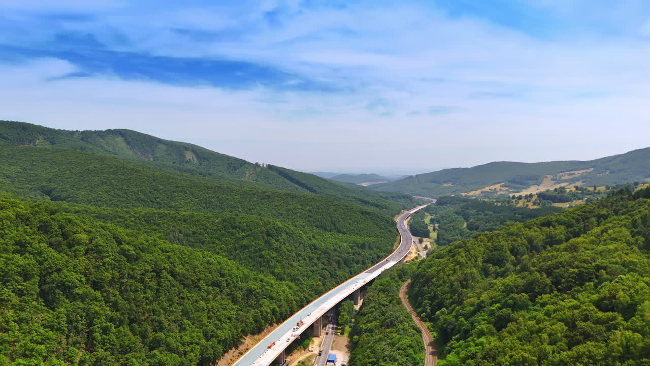 Hilly scenic winding road. A highway stretches through lush green hills, showcasing a tranquil landscape and clear blue skies in the distance