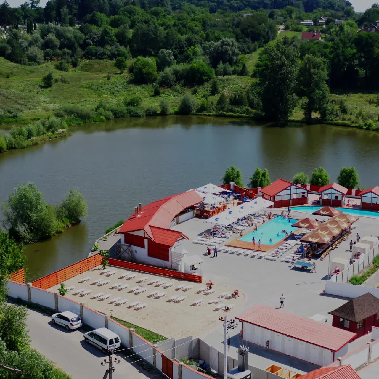 Aerial drone top view on a beautiful residential area. Outdoor swimming pools and green luch gardens near the river. Video from above