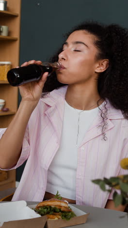 young woman enjoying a casual meal with a burger and a drink