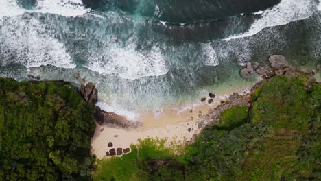 Overhead-drone-shot-of-uninhabited-White-sandy-beach-between-cliffs---Tropical-beach-of-Indonesia