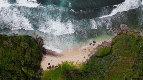 fotografía aérea con drones de una playa de arena blanca deshabitada entre acantilados - playa tropical de indonesia