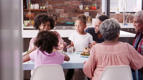 multi generation family praying before meal around table at home