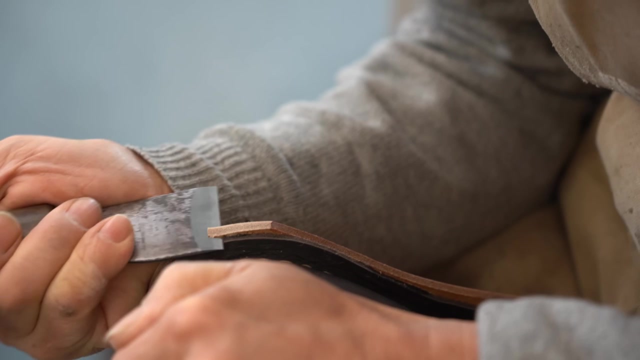 Craftsman flexing a thick leather midsole and fitting a steel shank while checking the arch of a handmade boot