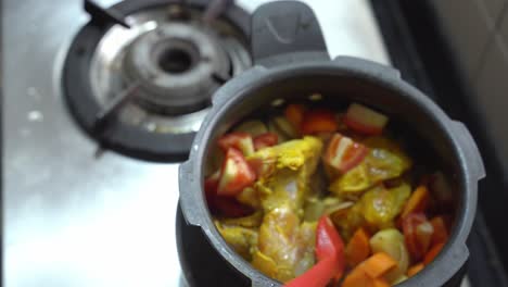 an asian man cooking chicken with indian spices coating, vegetables and curry leaves