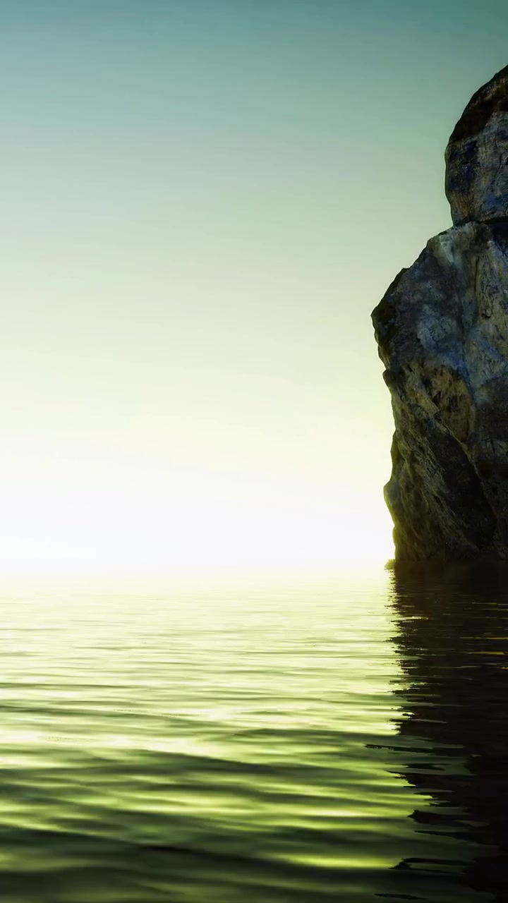 Sunrise over the calm water near a rocky shore with soft green hues