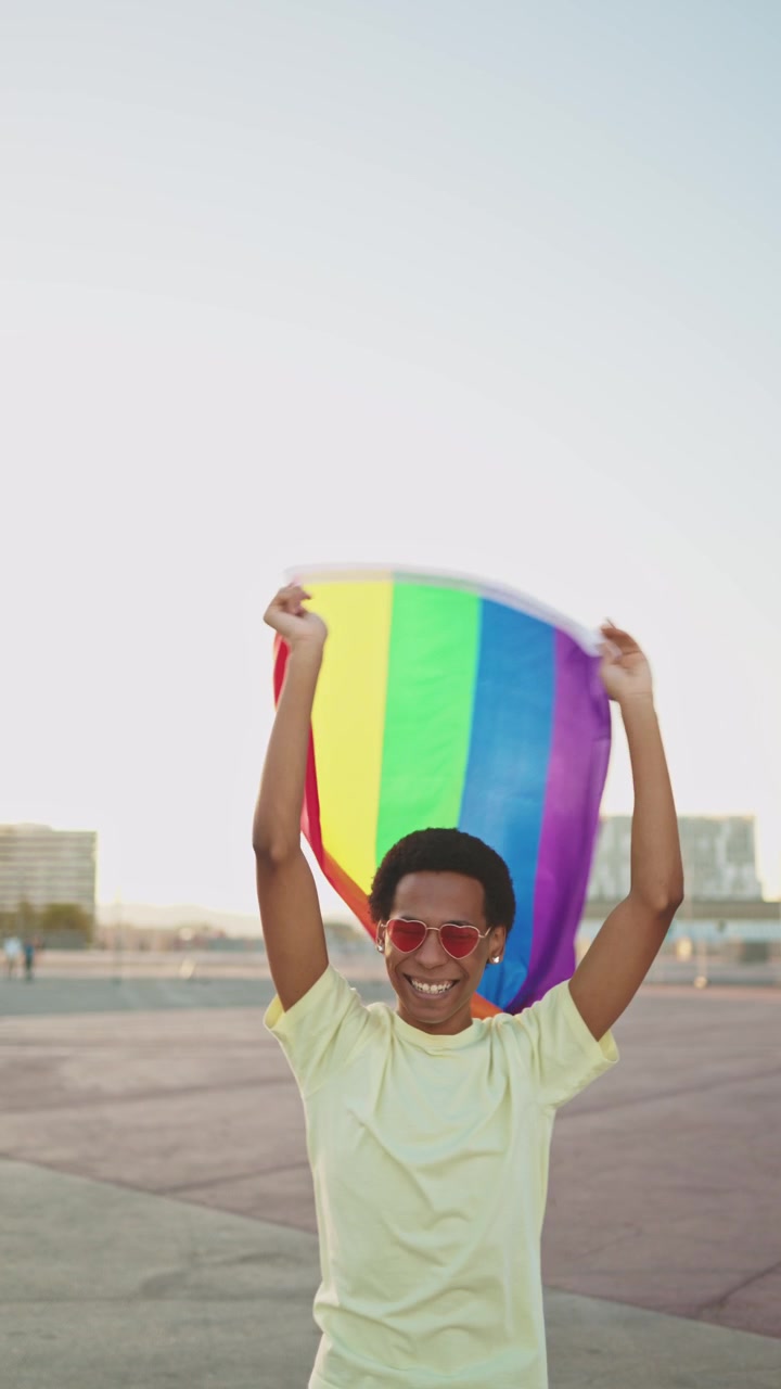Happy Young Man Waving Rainbow Pride Flag Outdoors