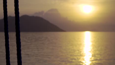 cámara panorámica desde un barco a una puesta de sol en la distancia con una cuerda cerca del barco