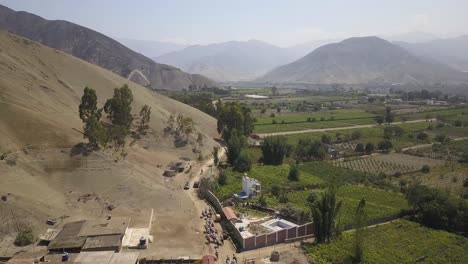 lush green fields contrast with arid hills as horse riders traverse a rural trail. a breathtaking aerial landscape ideal for travel, nature, or cultural photography.