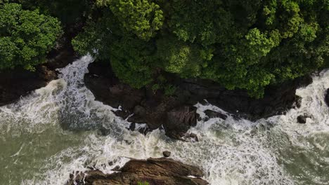 white foam ocean tide splashing against rocky coastline formations aerial birsdeye view dolly left