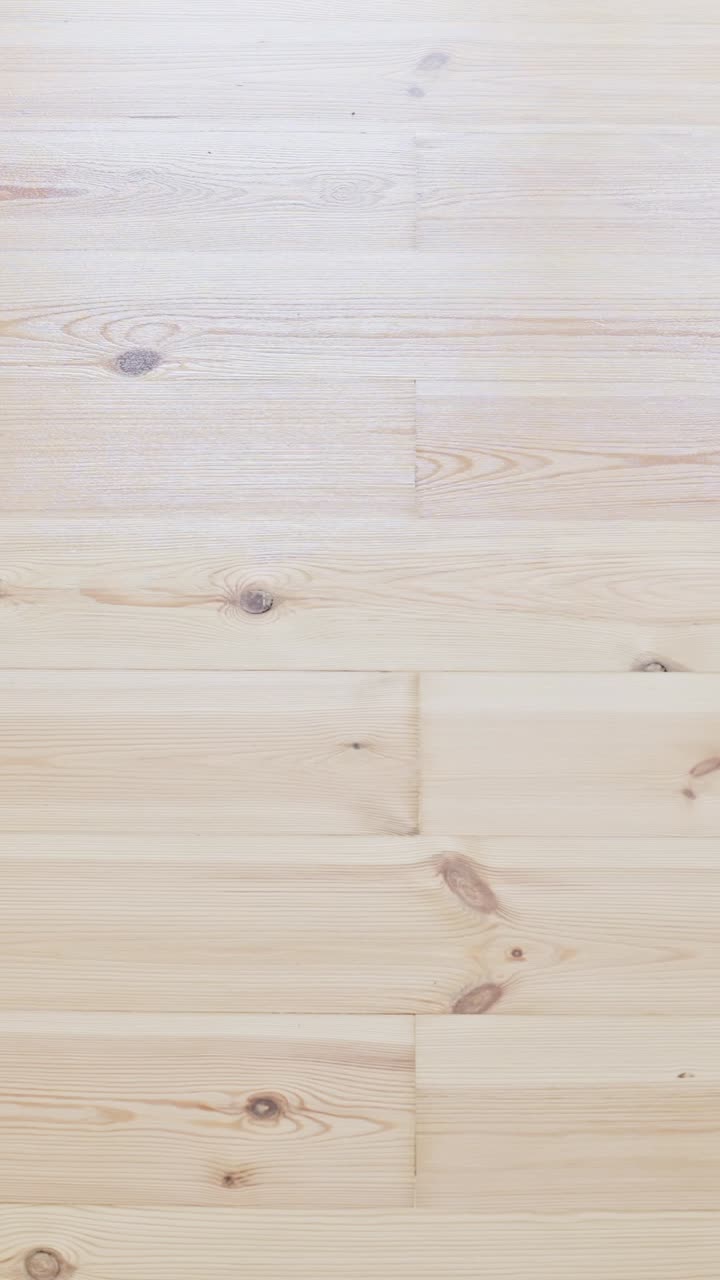 Renovation concept: worker varnishing natural pine wood floor with roller
