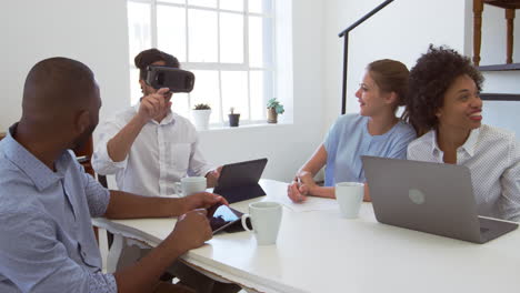 Hombre-Con-Gafas-De-Realidad-Virtual-En-Un-Escritorio-Con-Colegas-En-Una-Oficina