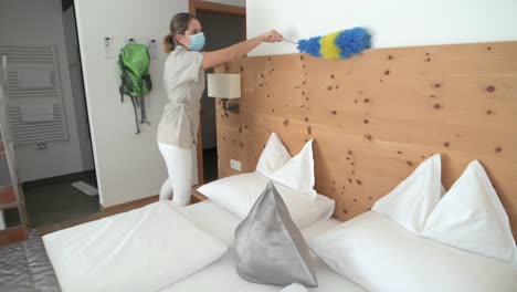 housekeeper with face mask cleans the hotel room