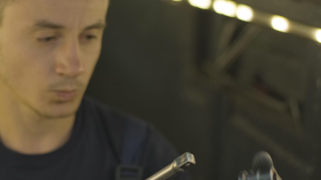 mecánico de automóviles que trabaja debajo de la máquina de elevación de automóviles en el garaje. taller de reparación de autos, servicio de automóviles, reparación.