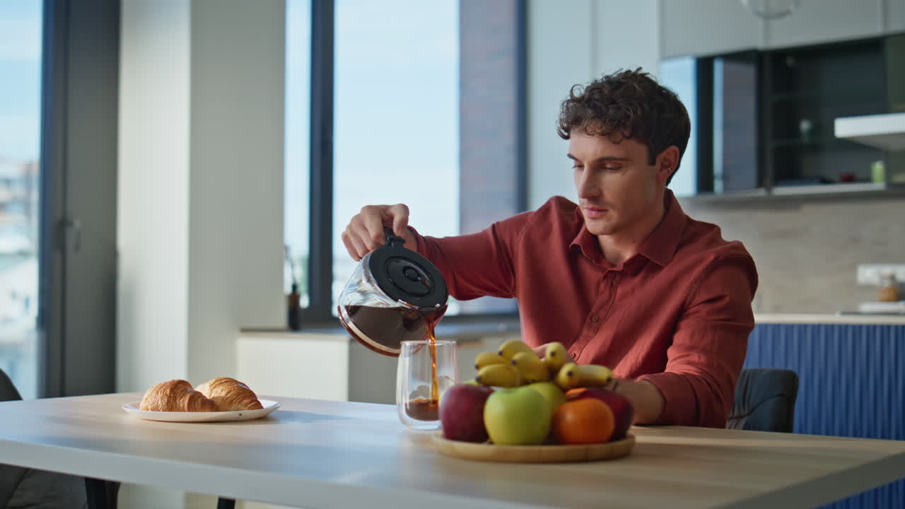 Thoughtful man pouring coffee sit down table modern kitchen closeup. Fresh fruit