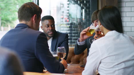 group of business colleagues meeting for drinks and socializing in bar after work