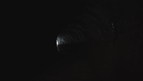 spooky interior of old railway tunnel with light in the distance