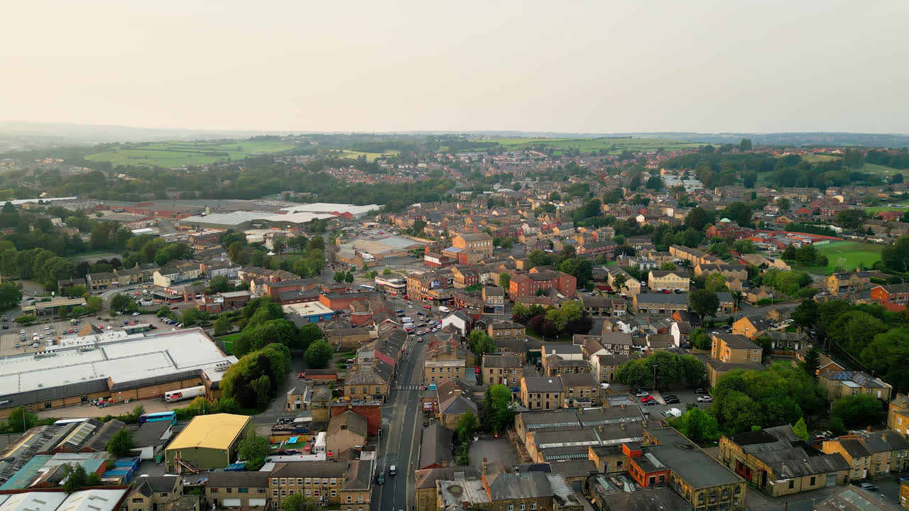 un avión no tripulado registra heckmondwike, reino unido, con edificios industriales, calles bulliciosas y el centro antiguo de la ciudad en una noche de verano
